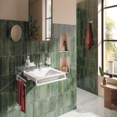 Bad mit grünen Fliesen, weißem Waschbecken und bunten Accessoires.